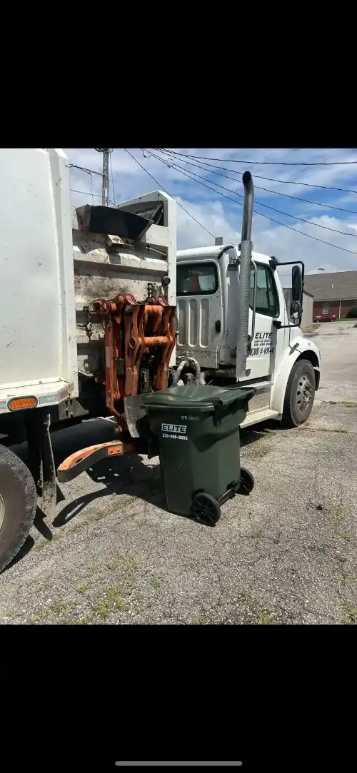 Elite Waste Services employee checking residential trash cart in front of house